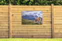 Een bruine koe in de Alpen op een poster aan een houten schutting.