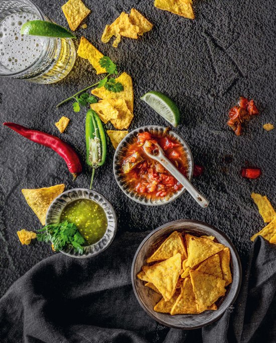 Tortillachips met twee soorten salsa, limoen en pepers.