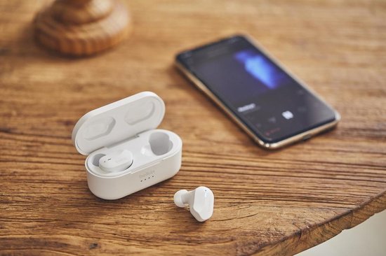 Witte oortelefoon en oplaadcase naast een smartphone.