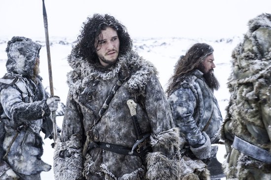 Jon Snow en twee metgezellen in dikke, met bont gevoerde winterkleding, met zwaarden en een speer, in de sneeuw.