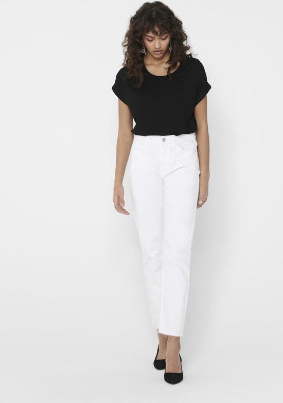 Vrouw draagt een zwarte top met opgerolde korte mouwen en een witte jeans met rafels aan de onderkant.