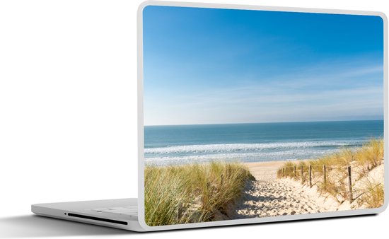 Ordinateur portable avec une image de plage : chemin de sable avec des poteaux en bois traversant les dunes vers une mer calme sous un ciel bleu.