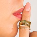 Vinger met gouden ringen bezet met gekleurde steentjes en diamanten voor een lippen aanraking.