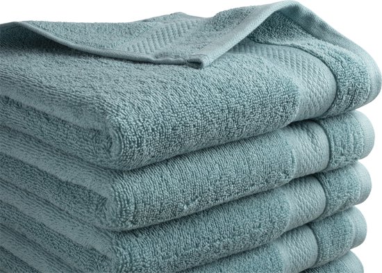 Gros plan d'une pile de serviettes de bain douces bleu clair avec un motif subtil sur les bords.