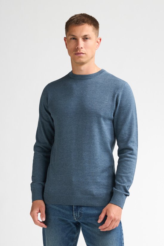Model draagt een blauwe, fijngebreide trui met ronde hals en regular fit.
