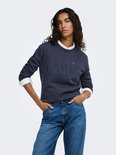 Model draagt een donkerblauw katoenen sweatshirt met "PARIS" in reliëf en een witte kraag, met de handen in de zakken van een jeans.