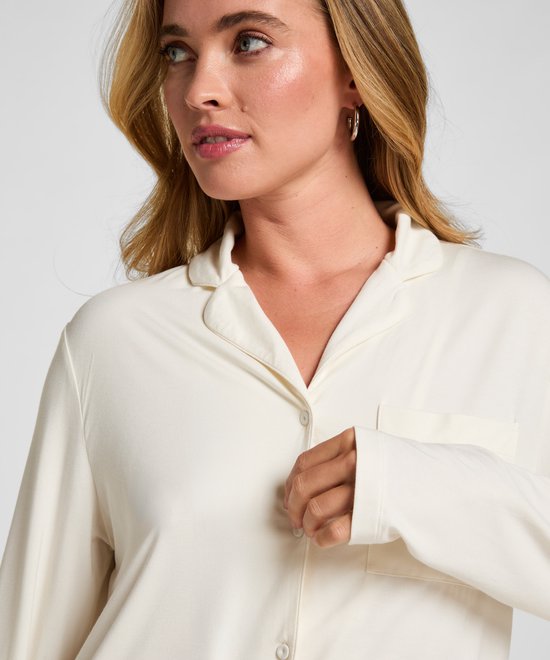Close-up van het crèmewitte pyjamashirt met knopen en borstzak.