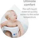 Een baby in een grijs badzitje lacht. De tekst zegt 'Ultiem comfort: het zachte materiaal warmt snel op tot watertemperatuur'.
