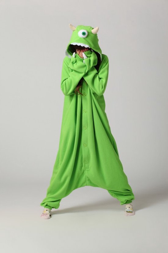 Groen monster onesie met kap, hoorns, oog en gebit. Een persoon staat met de armen voor het gezicht.