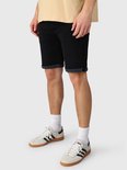 Model draagt zwarte denim shorts met opgerolde zomen, witte sokken en sneakers in een zijwaartse pose.