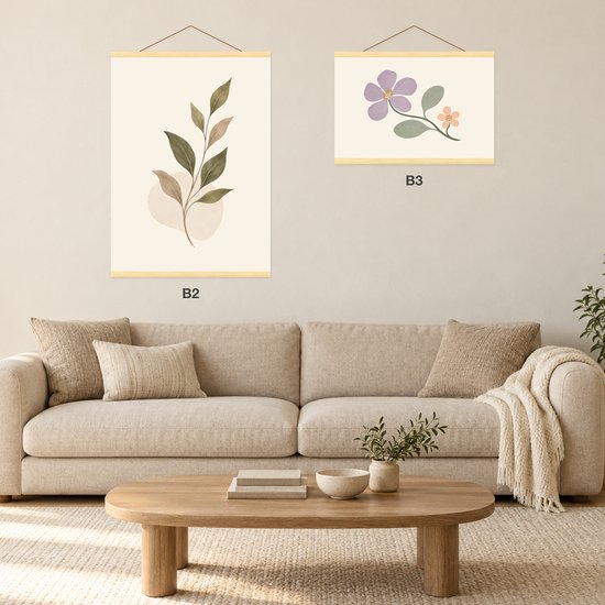 Woonkamer met een bank en twee ingelijste botanische prints (B2 en B3) aan de muur met houten posterhangers.