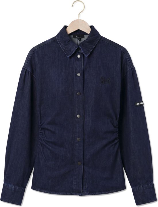 Donkerblauwe denim blouse aan een hanger. Met ruches aan de zijkant, knoopsluiting en zwarte opdruk op borst en mouw.