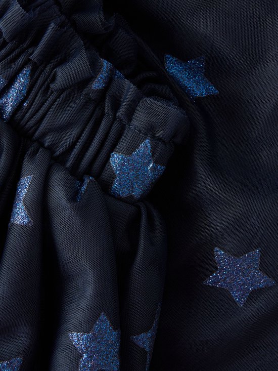 Detailopname van een donkerblauwe tule rok met glinsterende blauwe sterren en een elastische tailleband.