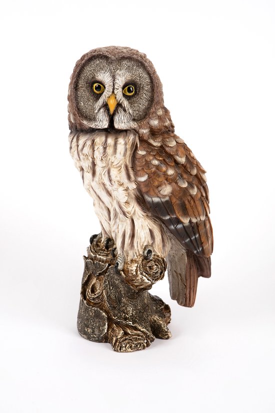 Statue décorative de grand hibou gris sur une souche d'arbre, avec des plumes brunes et grises et des yeux jaunes.