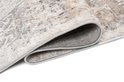 Gros plan détaillé du bord plié d'un tapis gris clair au motif délavé.