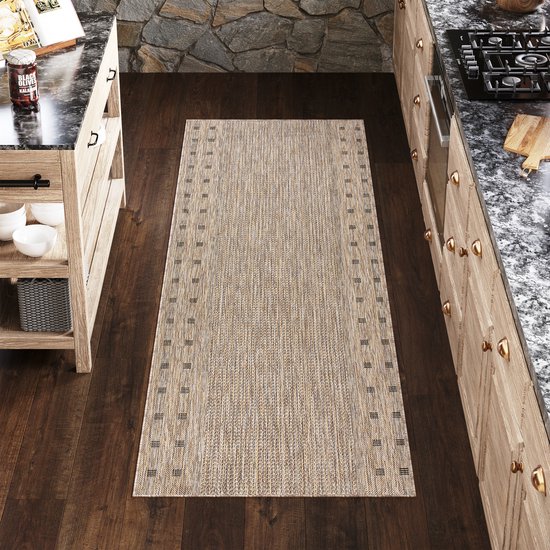Un tapis beige avec un motif décoratif sur les côtés, dans une cuisine avec des armoires en bois.