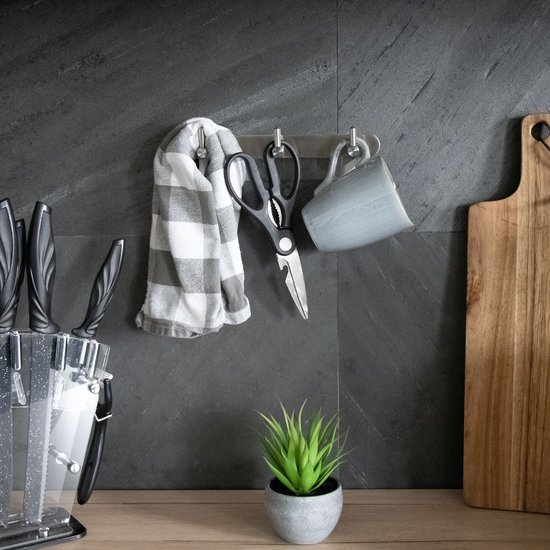 Trois crochets en acier inoxydable avec un torchon gris à carreaux, une paire de ciseaux et une tasse grise accrochés.