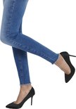 Blauwe skinny jeans met rafelige zoom, gedragen met zwarte pumps.