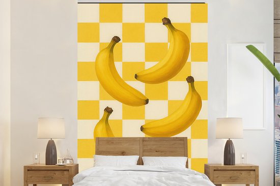 Fotobehang met gele bananen op een geel-wit geblokt patroon boven een tweepersoonsbed.