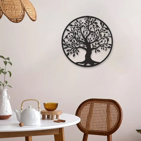 L'arbre de vie en métal noir est suspendu à un mur clair dans une salle à manger avec une table ronde et une chaise en rotin.