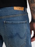 Detail van de achterkant van een blauwe jeans met leren label.