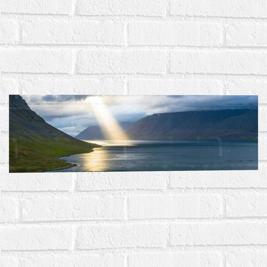 WallClassics - Muursticker - Zonnestraal op Water bij Bergen - 60x20 cm Foto op Muursticker