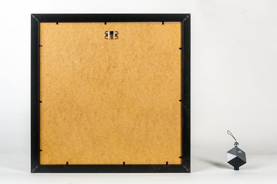 Achterkant van een zwarte fotolijst met ophangsysteem en een decoratief zwart object.