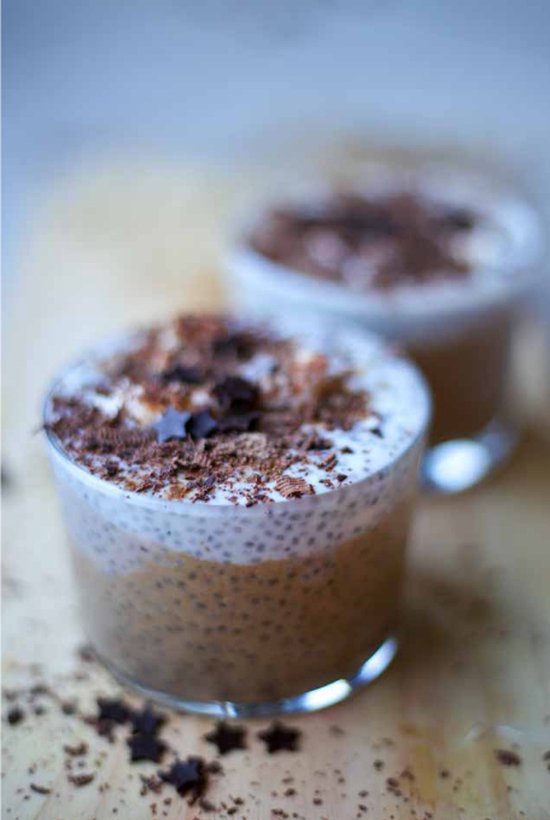 Twee glazen met chia pudding, gegarneerd met chocoladekrullen en sterren.