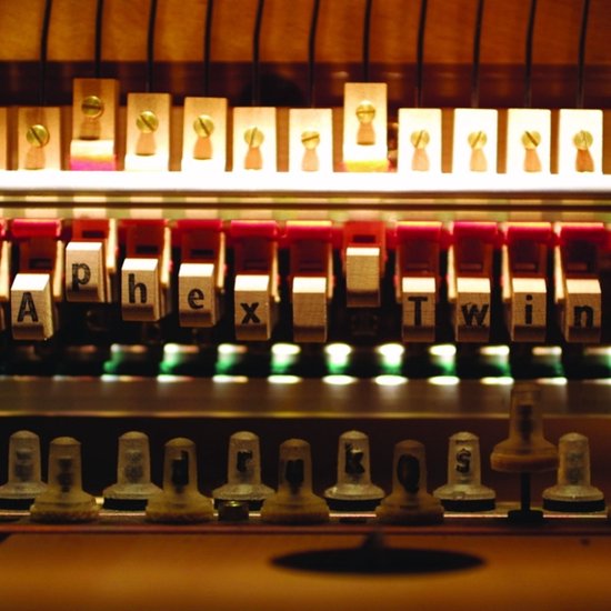 Geluidsapparatuur met witte toetsen met letters erop die 'Aphex Twin' spellen, onder rode knoppen.