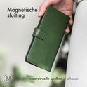 Hand die een groen telefoonhoesje in boekstijl vasthoudt. "Magnetische sluiting".