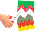 Hand knipt met schaar vellen met patronen: groen met krullen, roze met stippen en oranje met druppels.