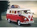 Een rode en witte PLAYMOBIL camperbus met twee figuren op een weg bij zonsondergang. Bagage op het dak.