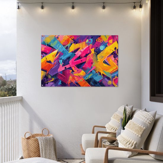 Een levendige abstracte graffiti poster hangt aan een witte muur op een balkon met twee stoelen en rieten manden.