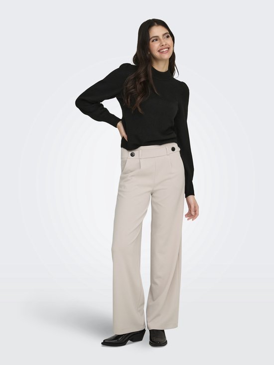 Model met beige wijde broek en zwarte top, zicht op de voorkant.