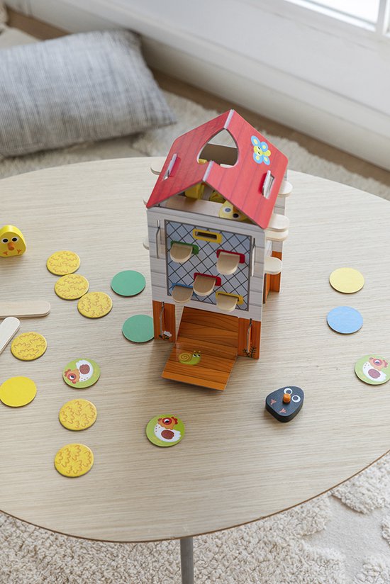 Kippenhok spel met gele kuikens op een ronde tafel, met een meisje dat aan het spelen is.