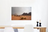 Canvas Schilderij Kamelen trek in de rode woestijn van Wadi Rum in Jordanië - 60x40 cm - Wanddecoratie