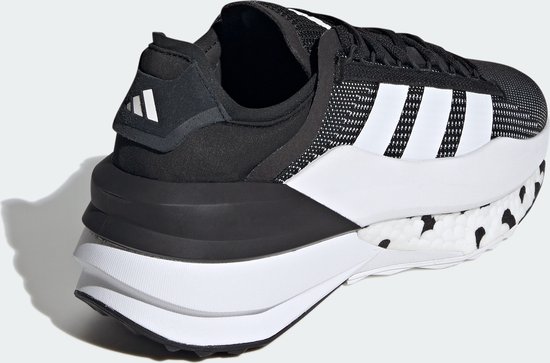 Chaussure de sport noire avec bandes Adidas blanches sur le côté et semelle blanche à pois noirs.