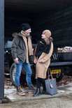 Man en vrouw met winterkleding en mutsen, staand bij een pick-up truck.