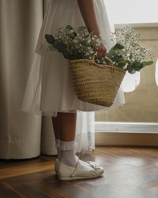 Meisjesbenen in witte sokken met kanten randje en roze schoentjes.