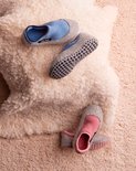 Lichtblauwe en roze pantoffels met grijze zolen en antislip noppen op een witte en beige achtergrond.