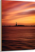 WallClassics - Hout - Vrijheidsbeeld in New York van Ver met Zonsondergang - 80x120 cm - 9 mm dik - Foto op Hout (Met Ophangsysteem)
