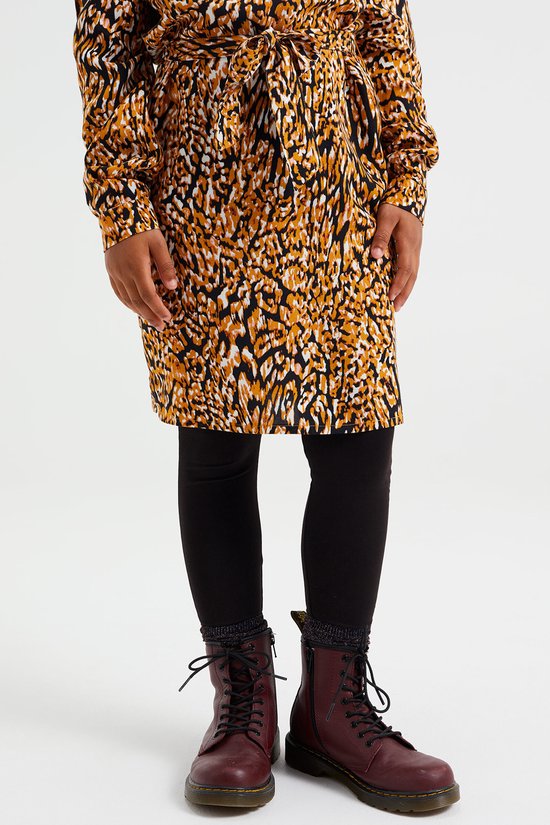 Meisje in een jurk met luipaardprint en zwarte legging.