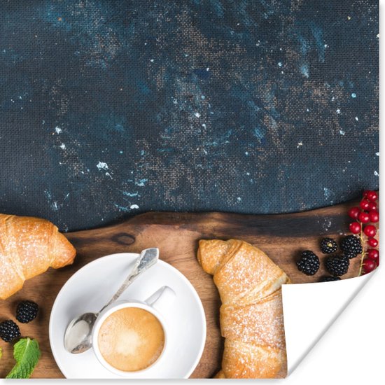 Petit déjeuner avec deux croissants, une tasse de café, des myrtilles, des mûres et des groseilles sur une planche en bois.