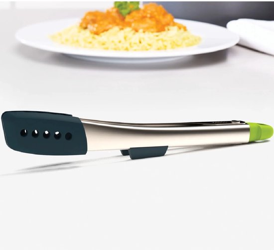 Pinces en acier inoxydable avec accents gris foncé et verts, posées sur un comptoir avec une assiette de nourriture en arrière-plan.