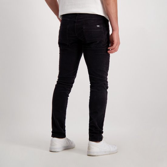 Achterkant van man in zwarte slim fit corduroy broek.