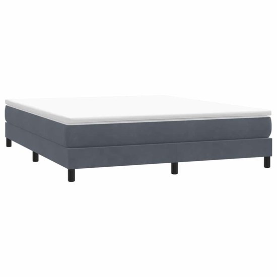 Donkergrijs fluwelen boxspring bedframe met een witte topper, op vier zwarte pootjes.