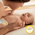 Moeder kust buikje van baby met Pampers luiertje aan. Cirkel toont detail van luier met hartje.