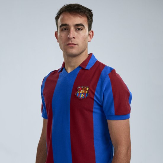 Jonge man met een FC Barcelona shirt met verticale blauwe en bordeauxrode banen, op een grijze achtergrond
