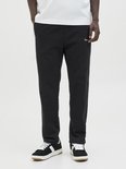 Close-up van een zwarte joggingbroek met geborduurde tekst 'Originals Studio'.