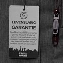Detail van een label op een donkergrijze rugzak met de tekst 'Levenslang Garantie' en een ritssluiting van TRVLMORE.